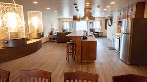 A spacious kitchen with a central island, wooden bar stools, and a large refrigerator.