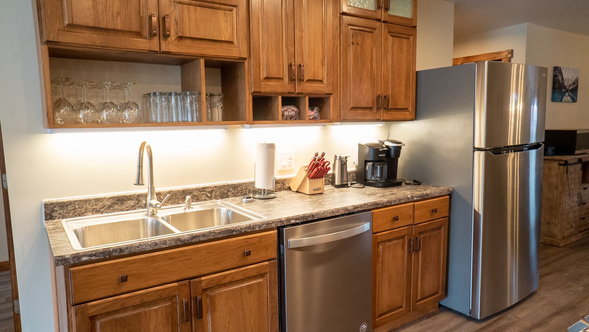 A kitchen with wooden cabinets, stainless steel appliances, a double sink, and a coffee maker.