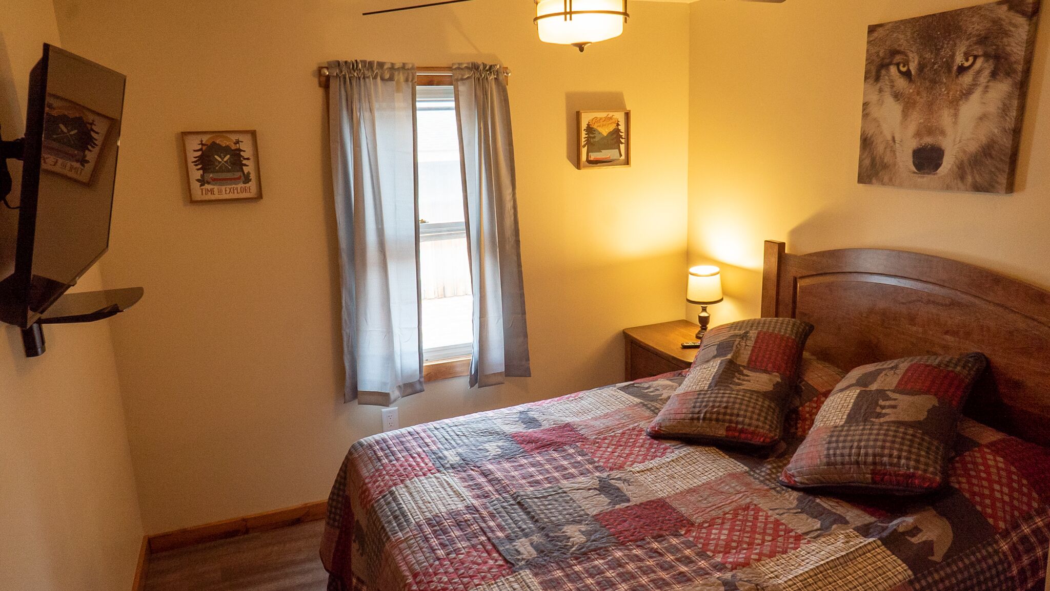 Un dormitorio con cama, mesita de noche, lámpara, ventana con cortinas y decoración en la pared.