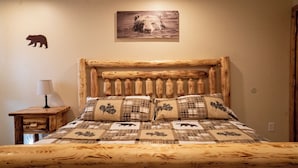 A wooden bed with a headboard, a bedside table with a lamp, and a bear silhouette on the wall.