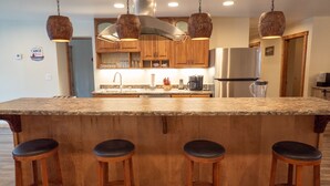 A kitchen with a large island, wooden cabinets, and pendant lights.