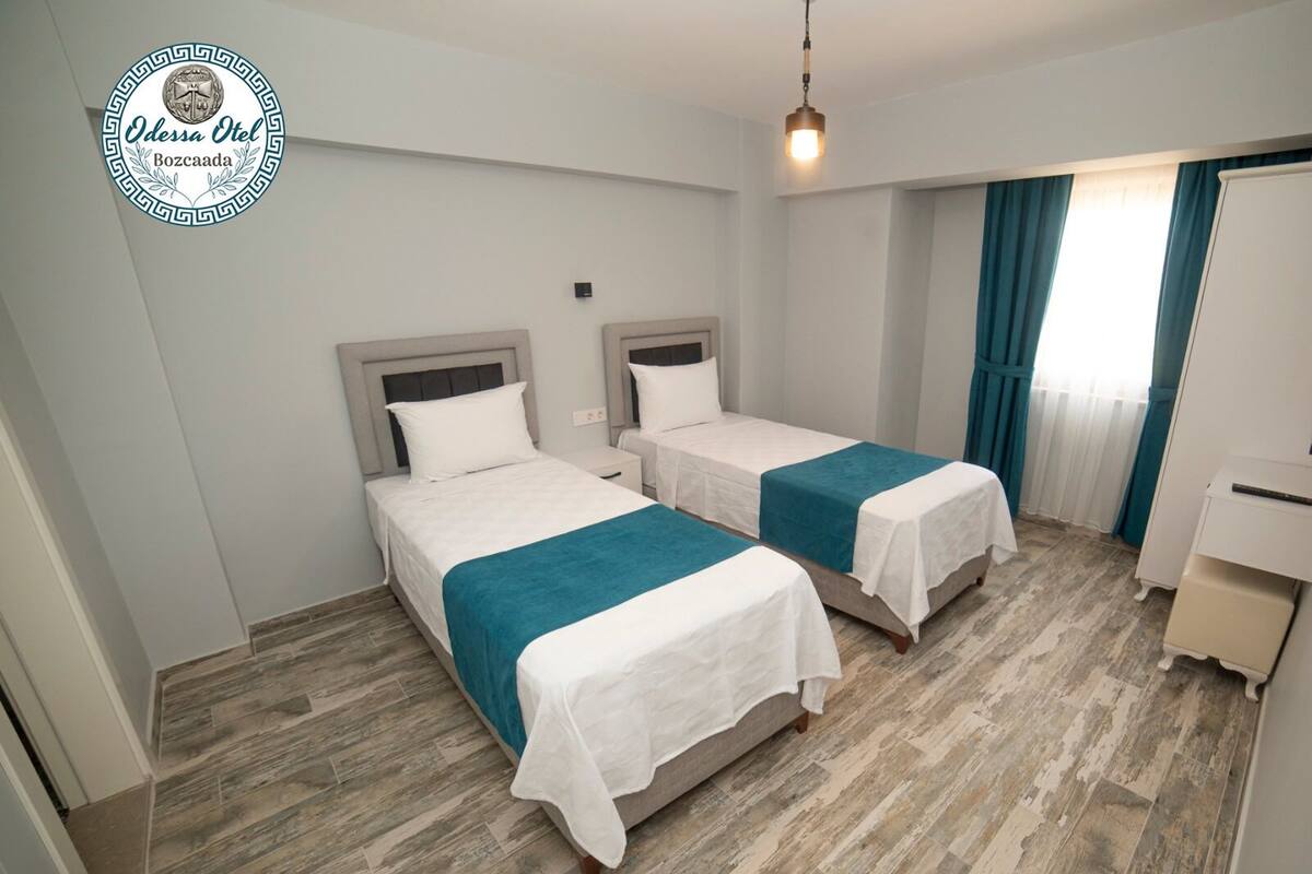 A hotel room with two beds, a desk, and a wardrobe.