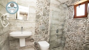 A bathroom with a sink, toilet, and shower. The walls are tiled with a geometric pattern. - Bozcaada Odessa  (Bozcaada)