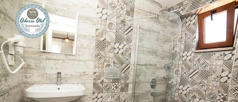 A bathroom with a sink, toilet, and shower. The walls are tiled with a geometric pattern.