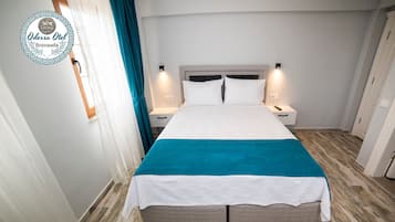 A hotel room with a bed, nightstands, and a teal accent on the bedspread.