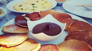 A table with various breakfast items including pancakes, a chocolate dessert, and multiple dishes. - Bozcaada Odessa  (Bozcaada)
