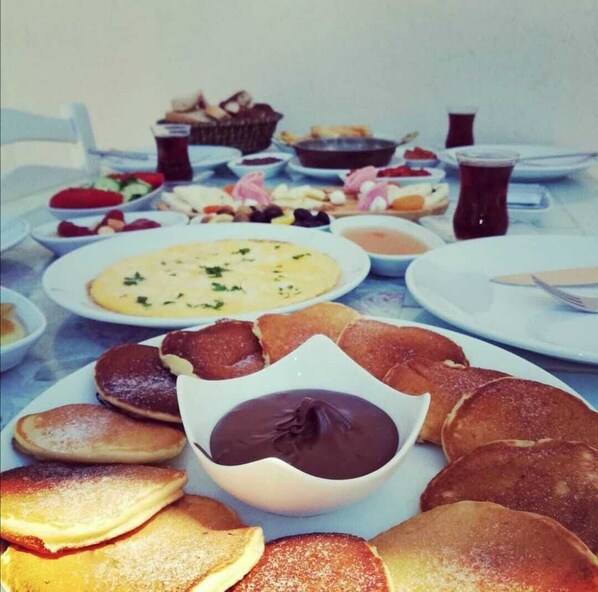 A table with various breakfast items including pancakes, a chocolate dessert, and multiple dishes.