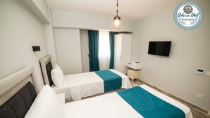 A hotel room with two beds, a TV, a desk, and a window with curtains. - Bozcaada Odessa  (Bozcaada)