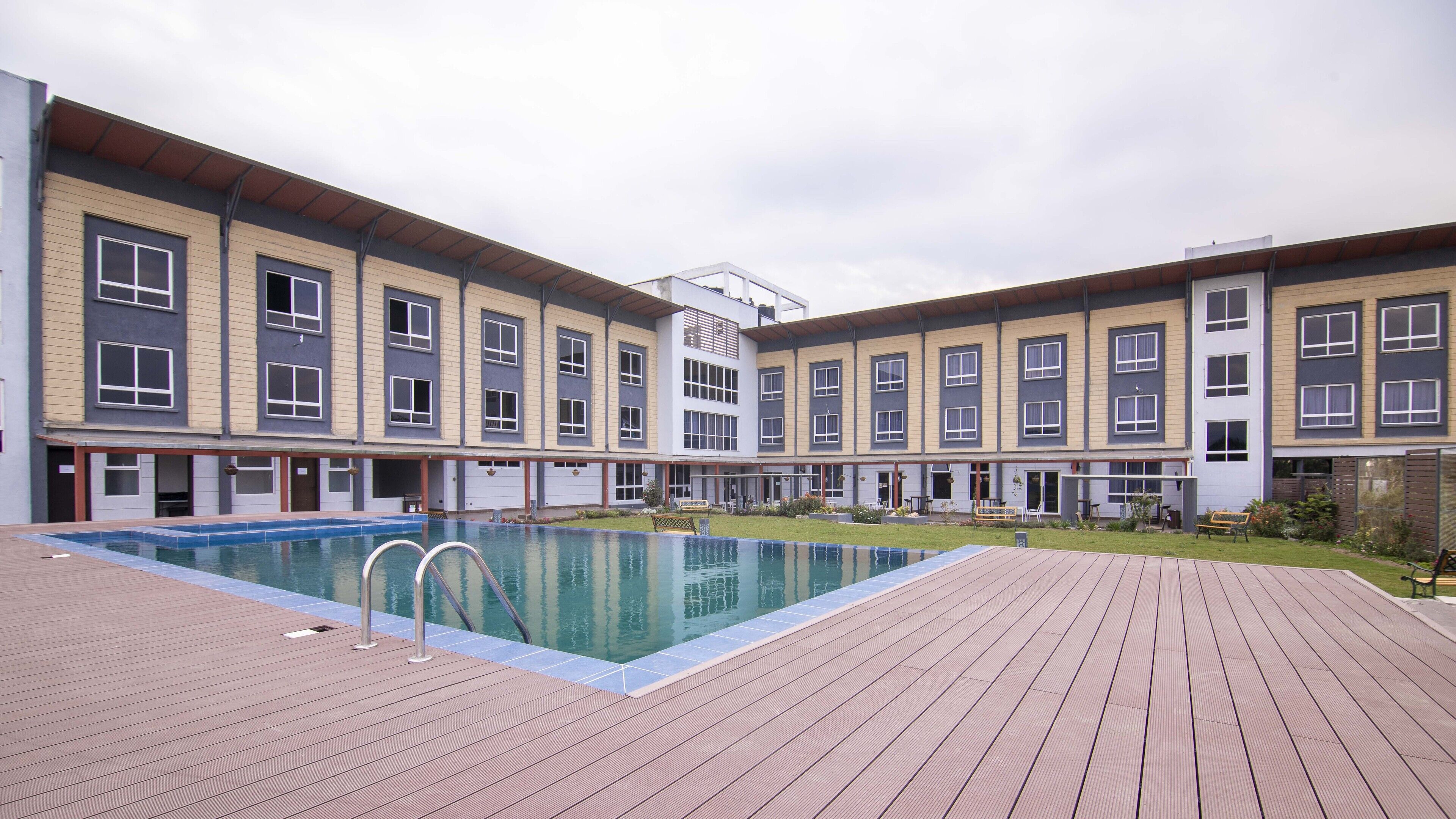 A modern building with a swimming pool and a wooden deck.