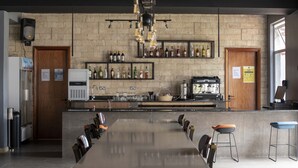 A modern bar area with a long counter, stools, and a variety of bottles on shelves.