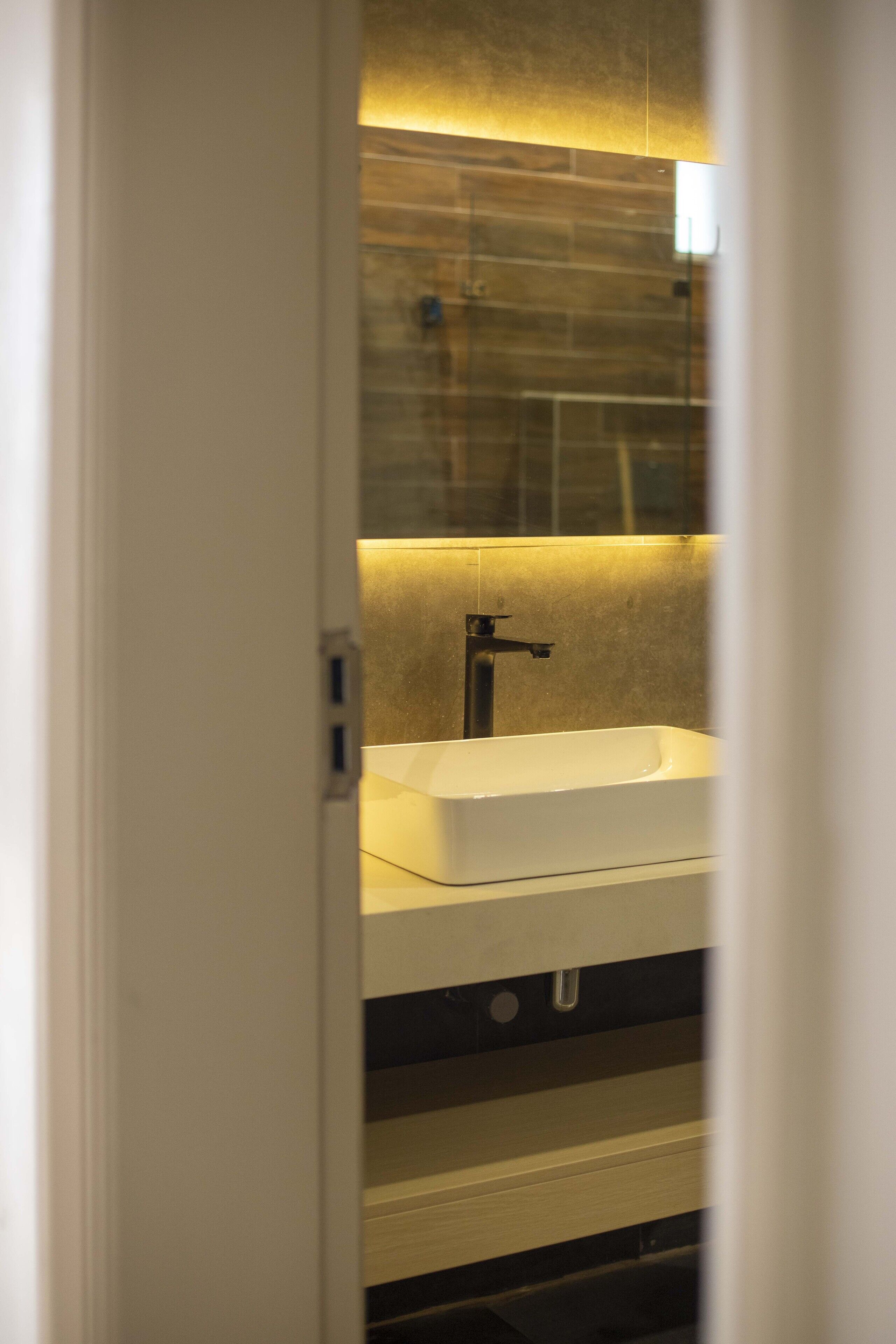 A bathroom with a white sink, a mirror, and a wooden wall.