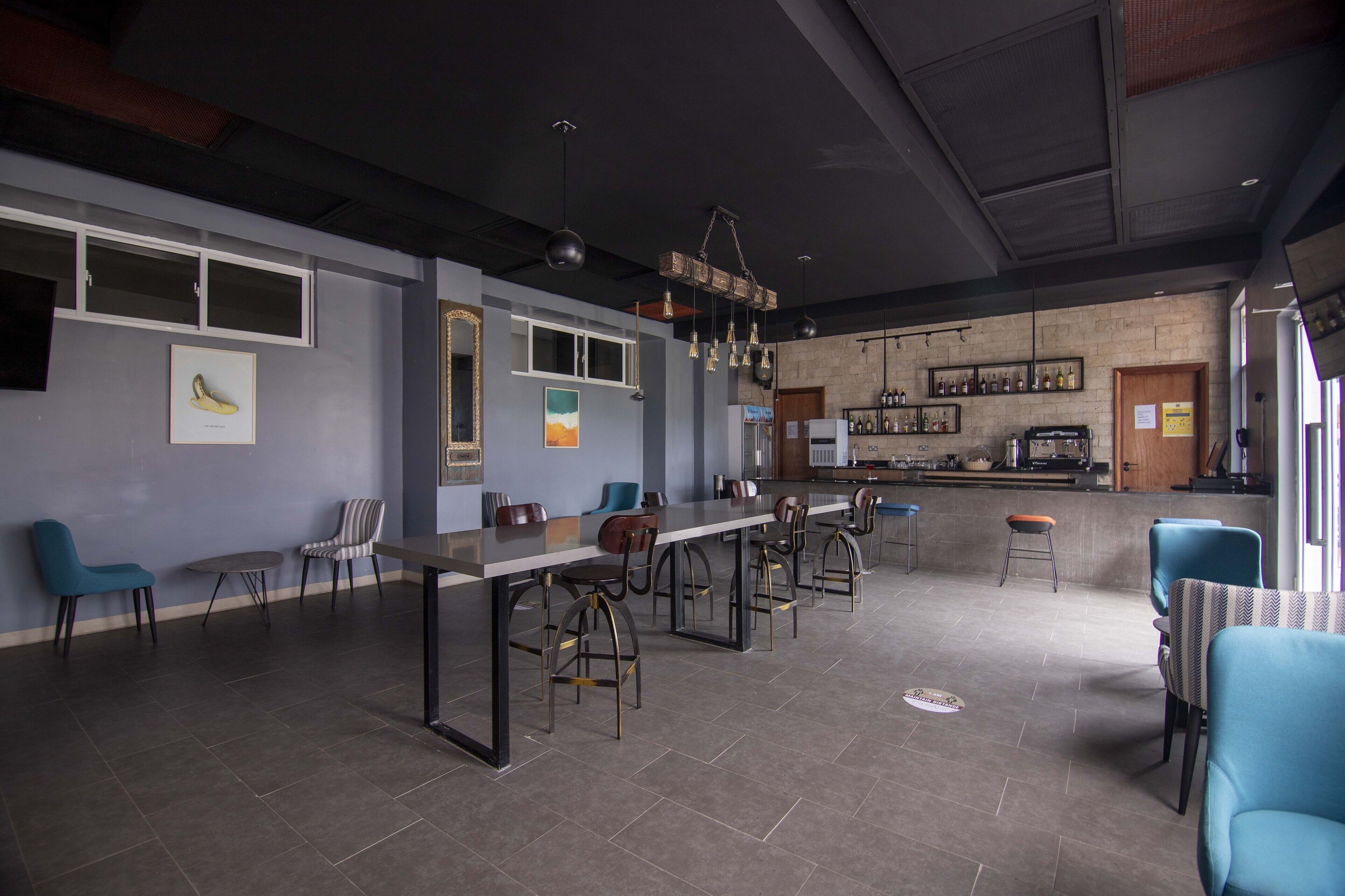 A modern restaurant with a long counter, multiple chairs, and a bar area.