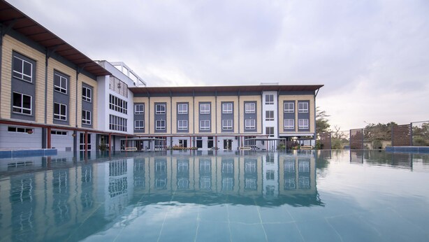 A swimming pool with a reflection of buildings, including a multi-story structure with large windows and a flat roof.