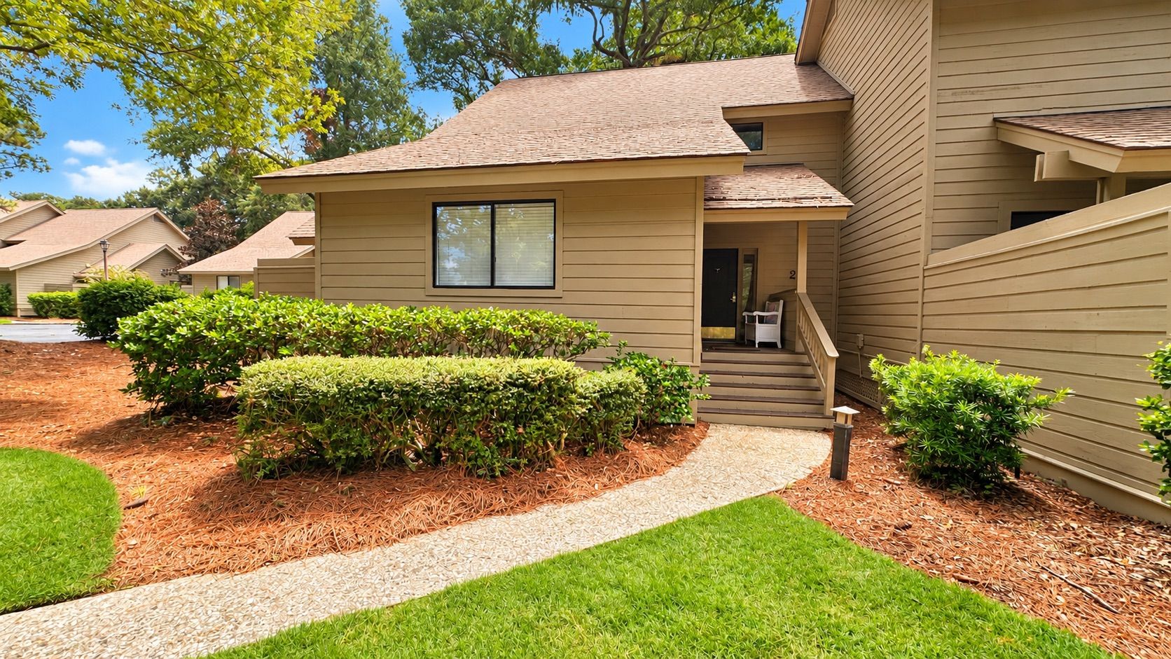 A residential building with a front porch, a pathway leading to the entrance, and well-maintained landscaping.