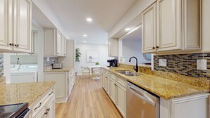 Una cocina moderna con encimeras de granito, electrodomésticos de acero inoxidable y armarios blancos.