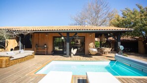A wooden villa with a swimming pool, outdoor seating, and a covered patio area.