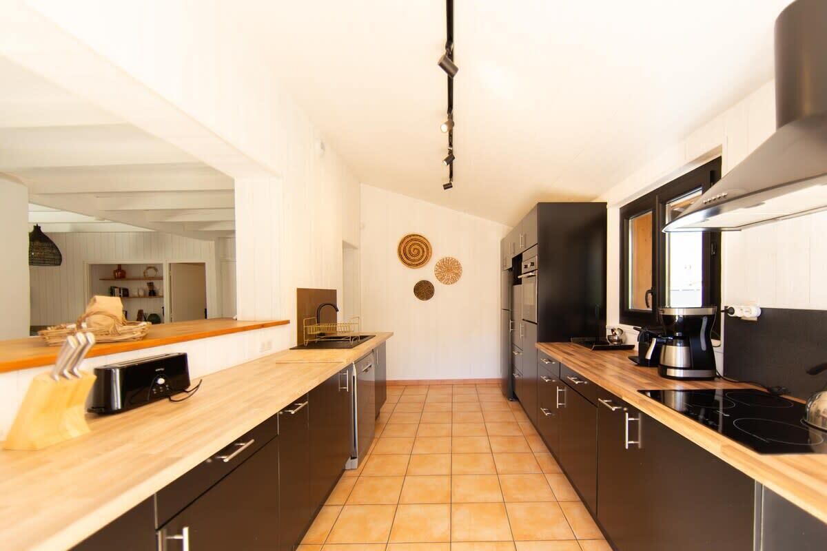 A modern kitchen with dark cabinets, a wooden countertop, and a black stove.