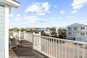 A wooden deck with a white railing, overlooking a residential area with houses and a clear sky. - A Modern Coastal Retreat Steps from the Gulf (Cape San Blas)