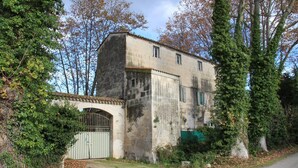 Ein zweistöckiges Gebäude mit einer Stein-Fassade, einem verschlossenen Eingang und umliegenden Bäumen.
