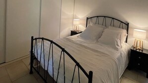 Ein Schlafzimmer mit Bett, Nachttischen, einer Pendelleuchte und eingebauten Schränken.