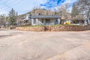 Une maison à deux étages, avec des fondations en pierre, un porche à l’avant et un garage.
