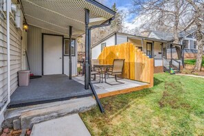 Un patio couvert, agrémenté d’une clôture en bois, de mobilier d’extérieur et d’une petite marche menant à la maison.