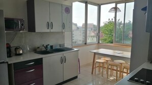 Eine moderne Küche mit weißen Schränken, einer Mikrowelle und einem Essbereich mit Tisch und Stühlen.
