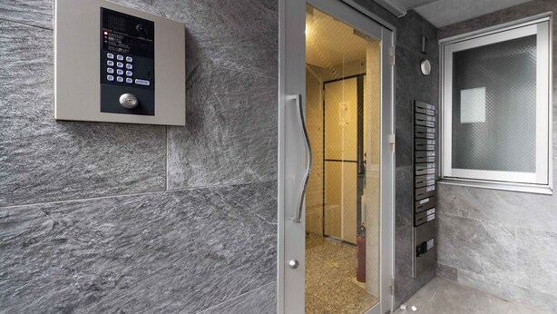 Un ascensor moderno con panel de control, puerta de vidrio y barandilla metálica.