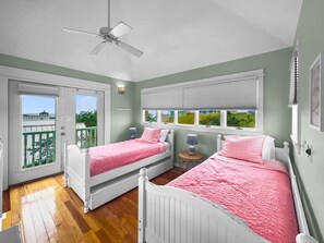 Quarto com duas camas, ventilador de teto e varanda com vista.