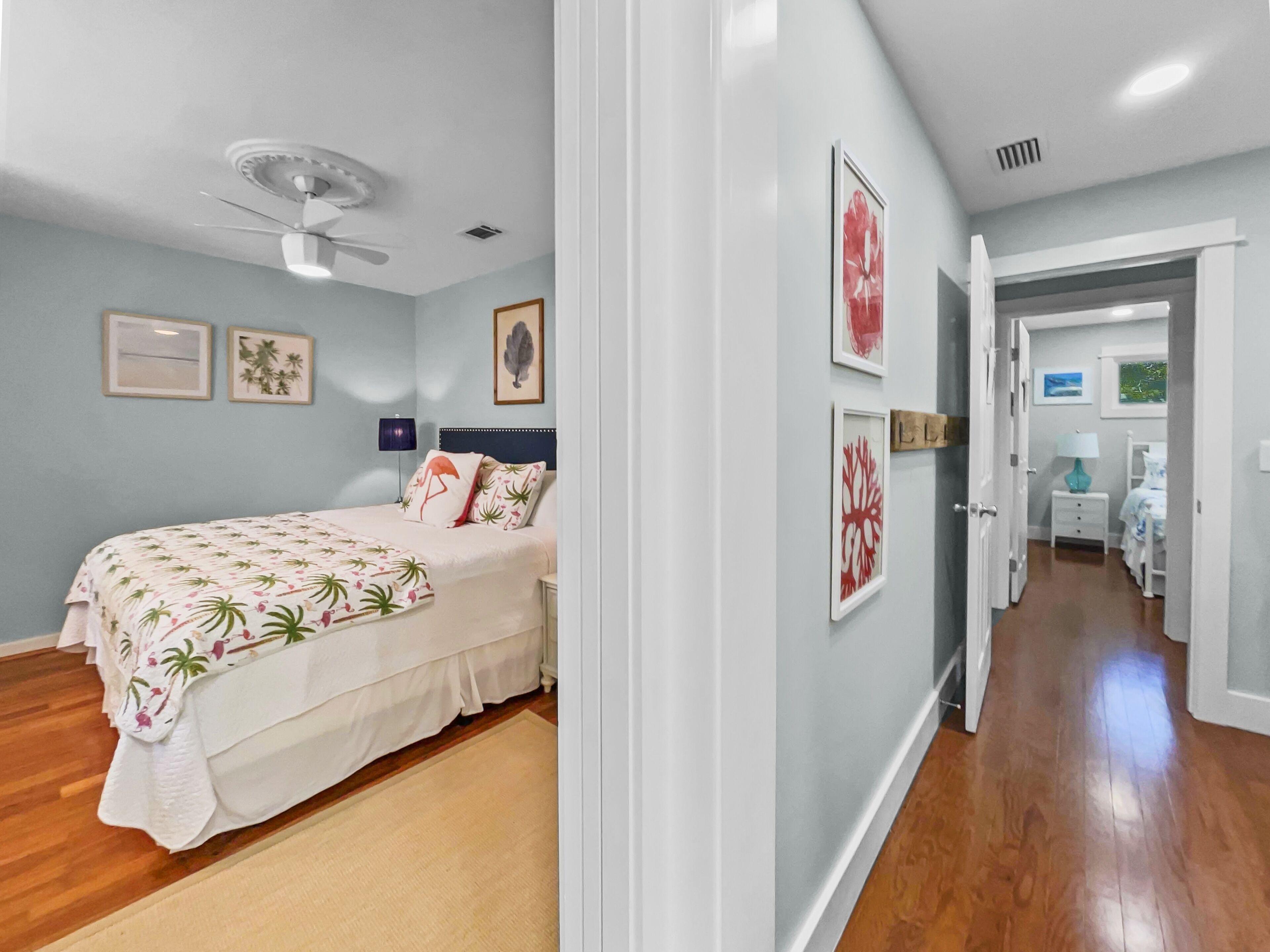 A bedroom with a bed, ceiling fan, and wall art.