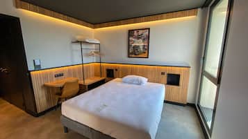 A hotel room with a bed, a desk, a chair, a TV, and a window.