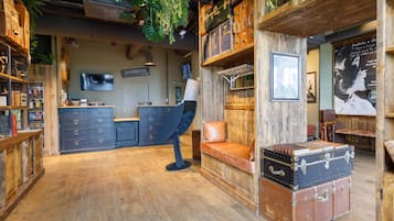 Une pièce rustique avec un plancher en bois, un bureau, un banc et des valises anciennes.