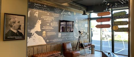 A modern interior with a large wall of quotes and a map, leather seating, and a view of the street outside.