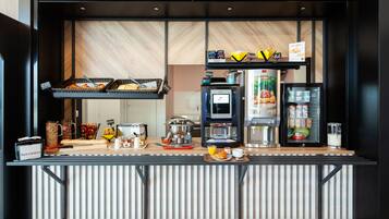 A breakfast bar with a coffee machine, a refrigerator, and various food items.