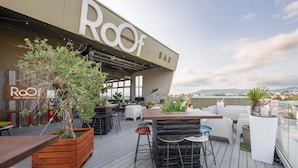 An outdoor seating area with a bar named "Roof" and a view of the city.