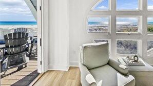 Ett rum med utsikt över stranden, en grå soffa och ett bord med dekorativa föremål.