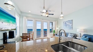 A modern kitchen with granite countertops, a stainless steel sink, and a dining area with a table and chairs.