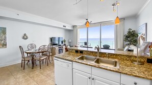 A modern kitchen with a large island, white cabinetry, and a view of the ocean.