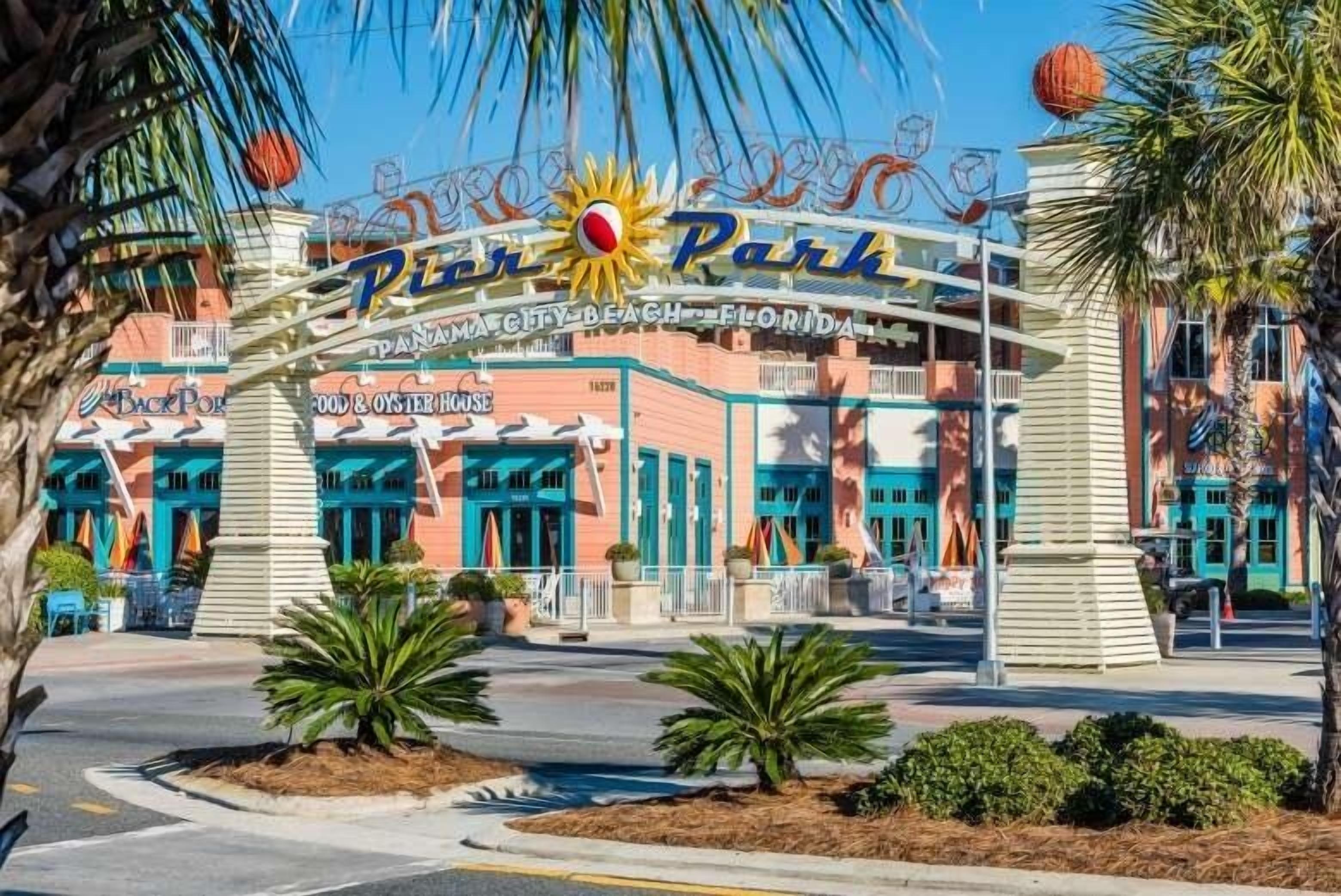 A building with a sign reading 'Panama City Beach, Florida' and 'Back Porch Food & Oyster House' with palm trees and a clear sky.