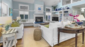 A spacious living room with a fireplace, white furniture, and a balcony with railings.