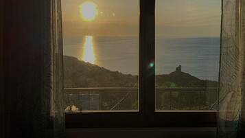 Une pièce dotée d’une grande fenêtre donnant sur un coucher de soleil sur la mer.