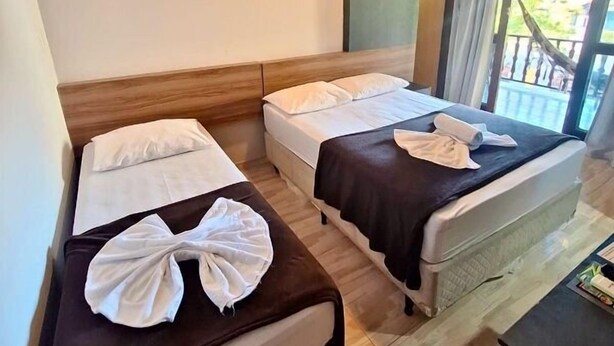 A hotel room with two beds, a desk, and a view of the outdoors. - Pousada Estrela Dalva (Penha)
