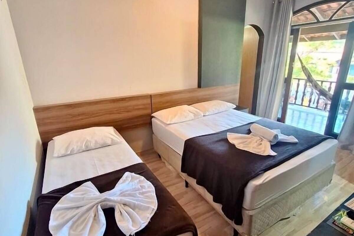 Quarto de hotel com duas camas, uma mesa e vista para o exterior.