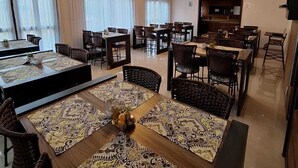 A spacious dining area with multiple tables and chairs, large windows with curtains, and a modern ceiling design. - Pousada Estrela Dalva (Penha)