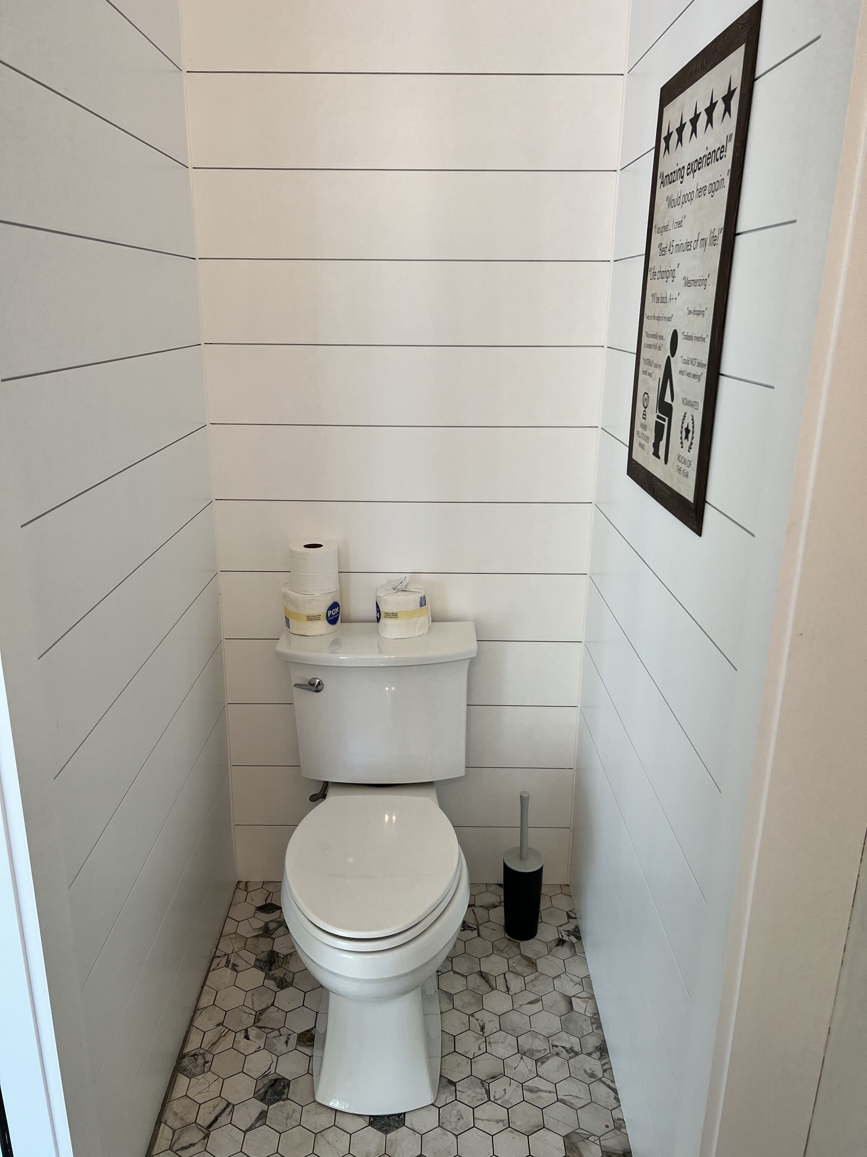 Un baño pequeño y limpio con inodoro, papel higiénico y secamanos.