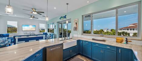 A modern kitchen with blue cabinets, a marble countertop, and a dishwasher.