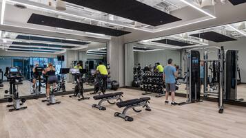 A modern gym with various exercise equipment, including treadmills, dumbbells, and weight machines.