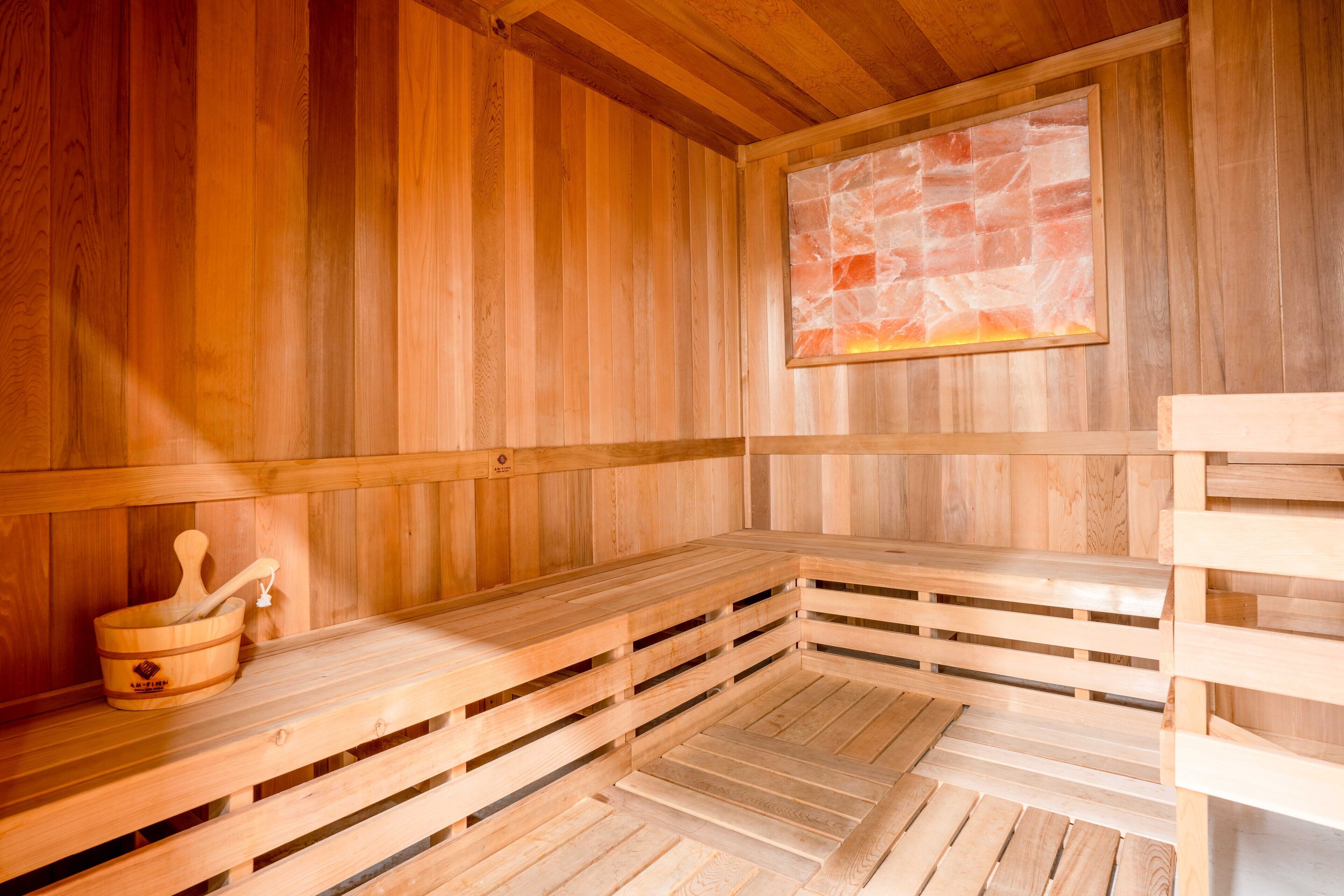 Een houten sauna met banken en een stenen muur.