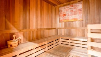 Een houten sauna met banken en een stenen muur.