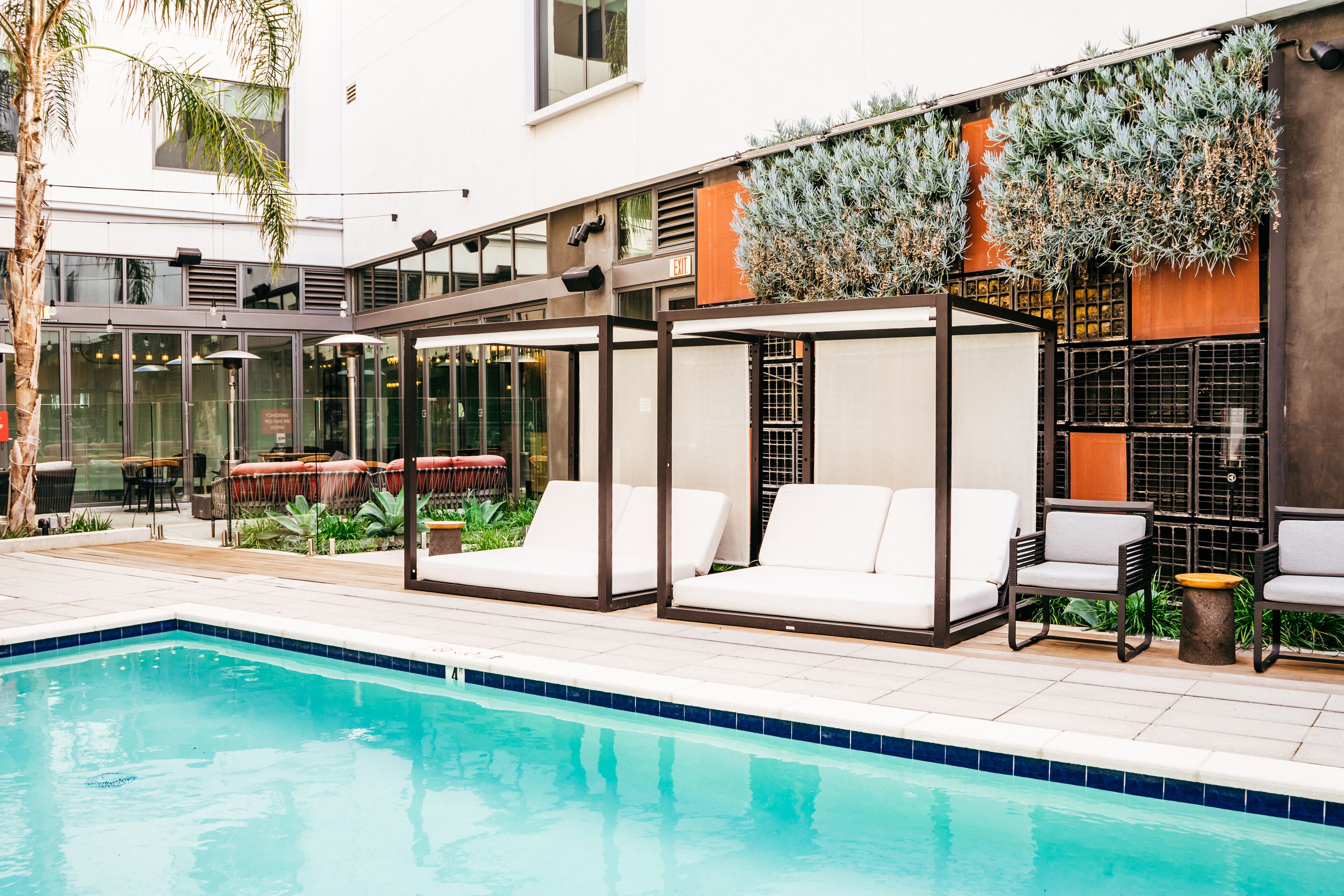 A poolside area with a glass-enclosed seating area, a pool, and outdoor furniture.